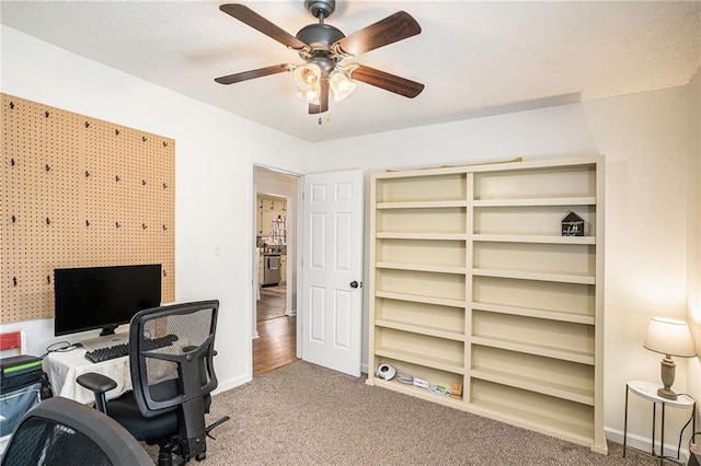 office featuring baseboards, a ceiling fan, carpet flooring, and a textured ceiling