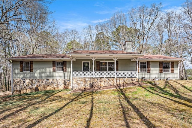ranch-style home with a chimney, covered porch, and a front lawn