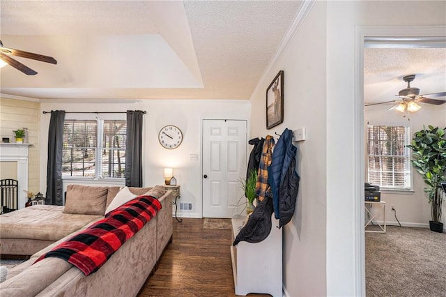 living area with visible vents, a textured ceiling, ornamental molding, and a ceiling fan
