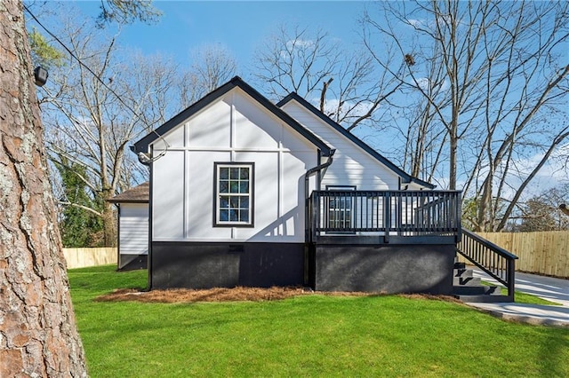 exterior space featuring stairs, a lawn, a wooden deck, and fence