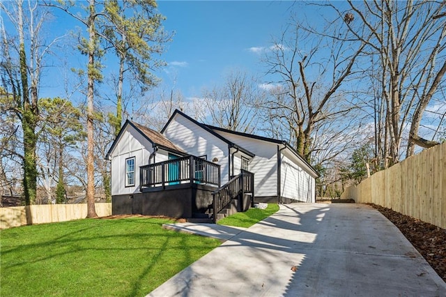 view of front of home featuring concrete driveway, fence, stairway, and a front lawn