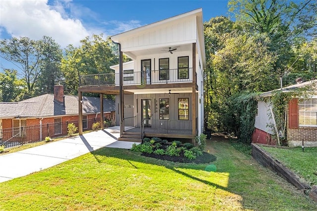 view of front of house featuring covered porch, concrete driveway, a ceiling fan, a balcony, and a front lawn