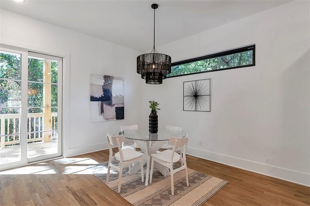 dining room with baseboards, wood finished floors, and an inviting chandelier