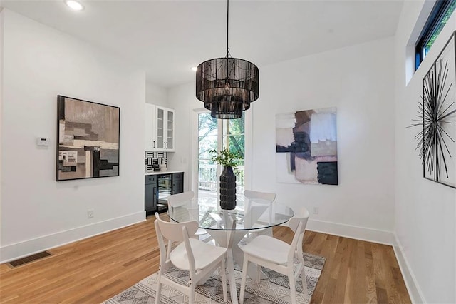 dining room featuring a chandelier, light wood-type flooring, visible vents, and baseboards