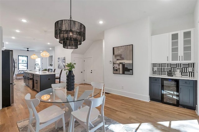 dining space with a notable chandelier, recessed lighting, light wood-style flooring, beverage cooler, and baseboards