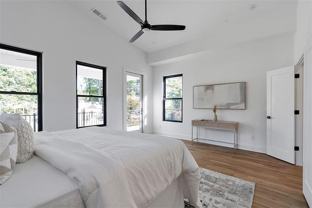 bedroom with high vaulted ceiling, wood finished floors, visible vents, and baseboards