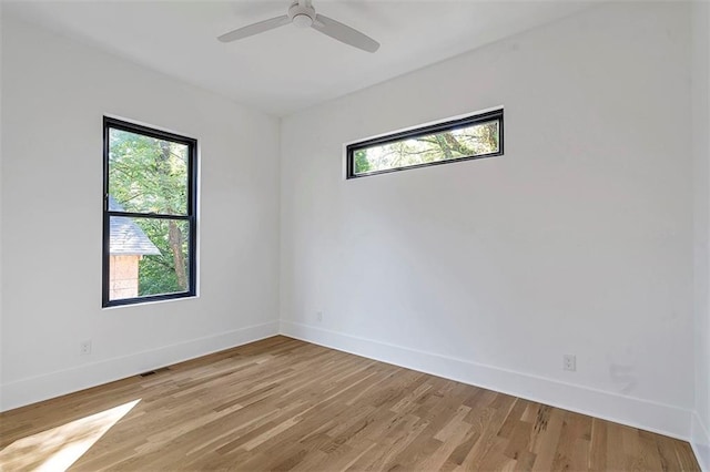 unfurnished room with baseboards, plenty of natural light, visible vents, and light wood-style floors