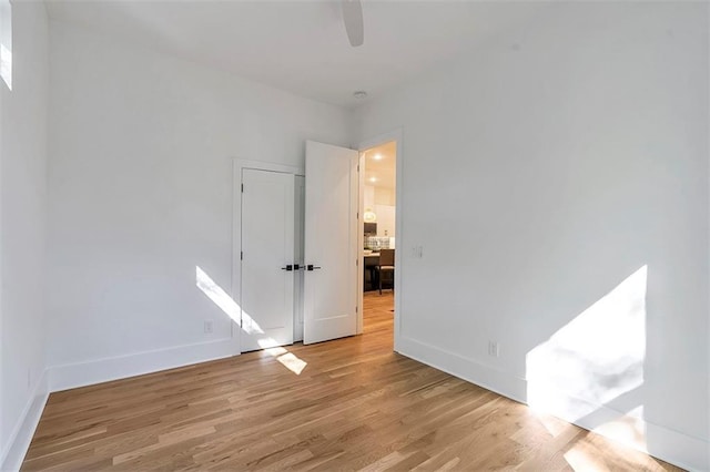 spare room featuring ceiling fan, light wood-style flooring, and baseboards