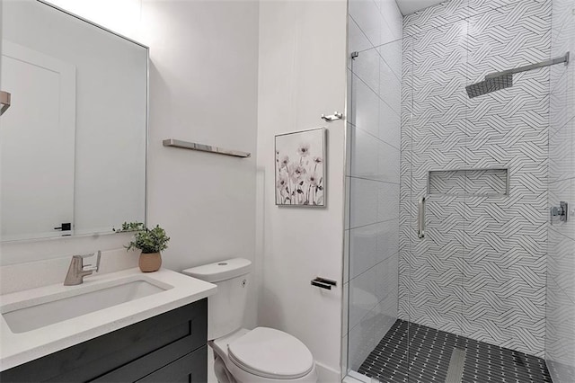 bathroom with tiled shower, vanity, and toilet