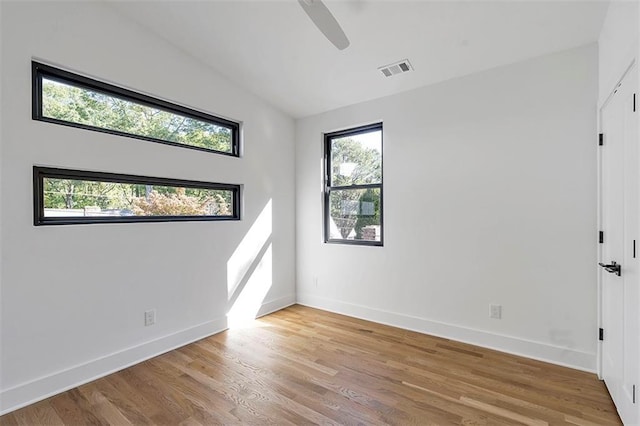 empty room with lofted ceiling, light wood-type flooring, visible vents, and baseboards