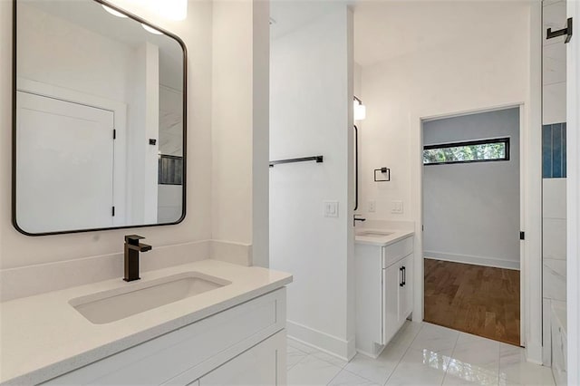 full bath featuring two vanities, a sink, and baseboards