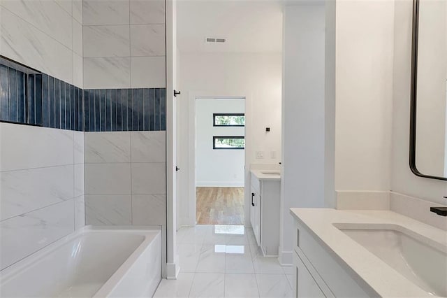 full bathroom with two vanities, visible vents, a bathing tub, a sink, and walk in shower