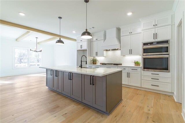 5808 Swinging Gate Rd, Gainesville, GA 30506 - kitchen with premium range hood, light countertops, white cabinets, a sink, and a notable chandelier