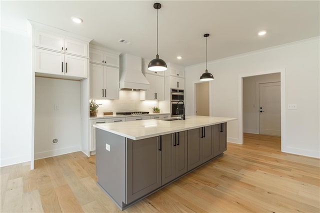 5808 Swinging Gate Rd, Gainesville, GA 30506 - kitchen featuring tasteful backsplash, white cabinets, custom exhaust hood, light wood-style floors, and an island with sink