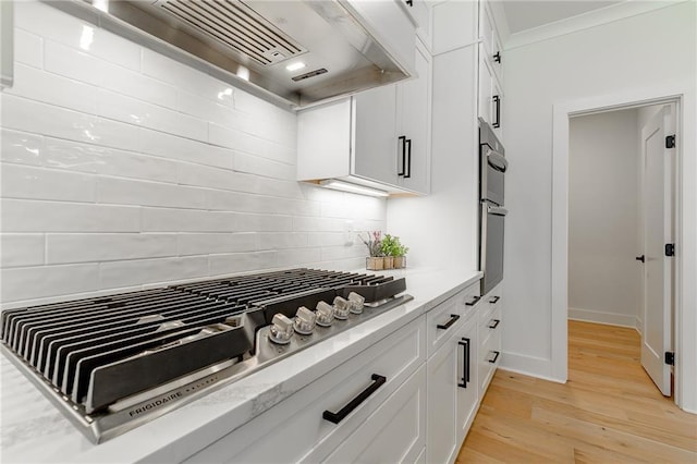 5808 Swinging Gate Rd, Gainesville, GA 30506 - kitchen with tasteful backsplash, stainless steel gas cooktop, light wood-type flooring, custom exhaust hood, and white cabinetry