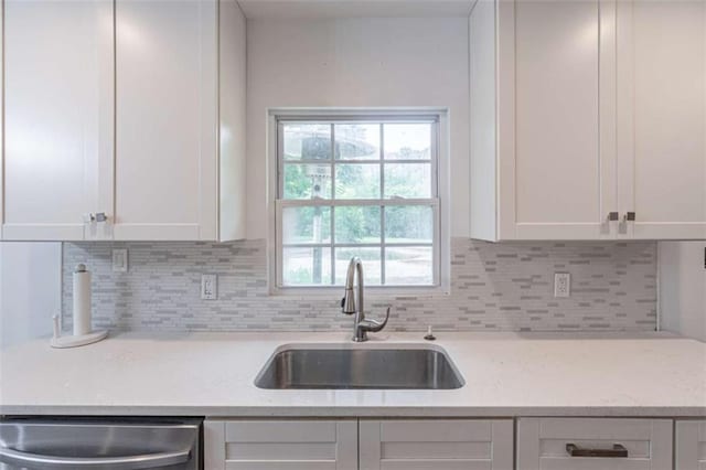 4408 Shiloh Trl, Powder Springs, GA 30127 - kitchen with stainless steel dishwasher, white cabinetry, tasteful backsplash, and light stone counters