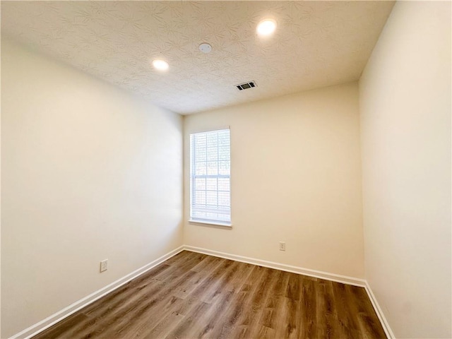 unfurnished room with a textured ceiling and hardwood / wood-style flooring