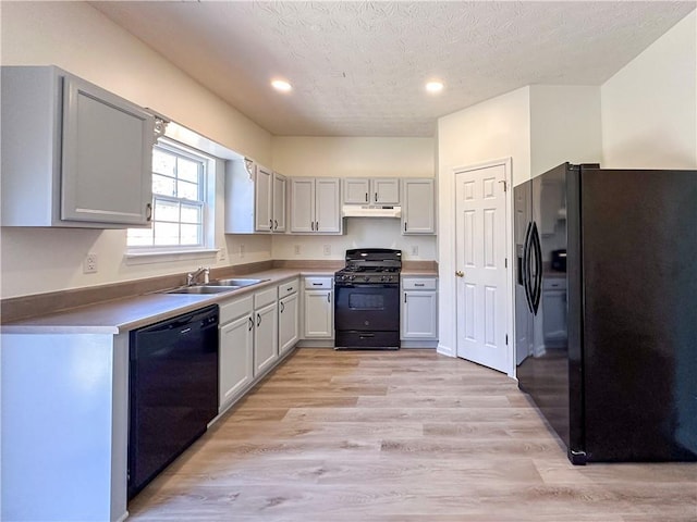 kitchen with black appliances, light hardwood / wood-style floors, sink, and a textured ceiling