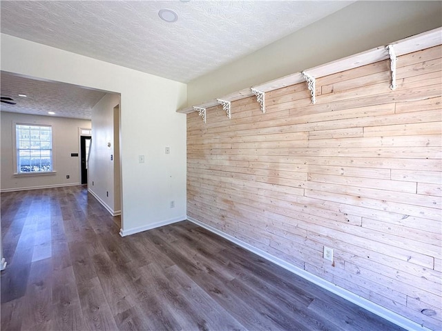 unfurnished room featuring dark hardwood / wood-style floors, a textured ceiling, and wooden walls