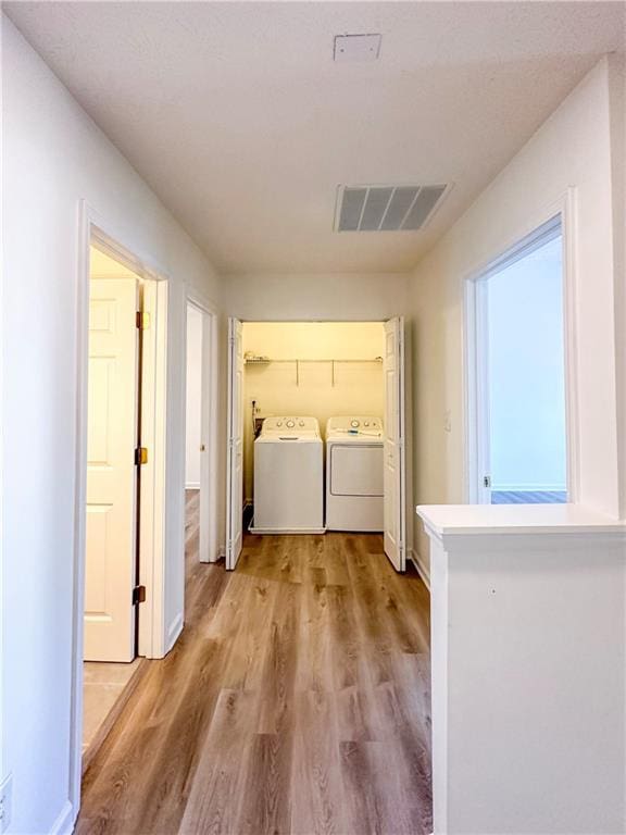 clothes washing area featuring light hardwood / wood-style floors and separate washer and dryer