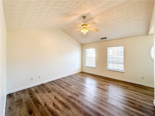 unfurnished room featuring ceiling fan, dark hardwood / wood-style flooring, lofted ceiling, and a textured ceiling