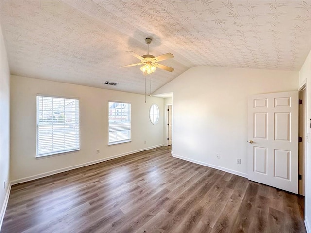 empty room featuring dark hardwood / wood-style floors, ceiling fan, a textured ceiling, and vaulted ceiling