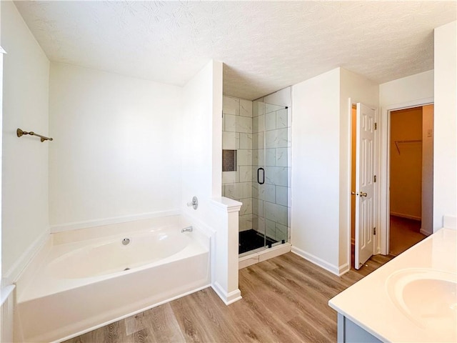 bathroom with hardwood / wood-style floors, vanity, a textured ceiling, and shower with separate bathtub