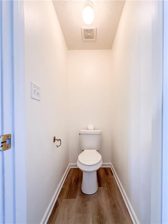 bathroom featuring wood-type flooring, a textured ceiling, and toilet