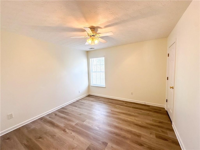 empty room featuring ceiling fan, dark hardwood / wood-style flooring, and a textured ceiling