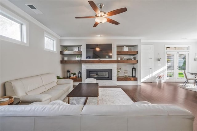1055 Peyton View Ct, Alpharetta, GA 30004 - living room featuring a ceiling fan, wood finished floors, a glass covered fireplace, ornamental molding, and built in features