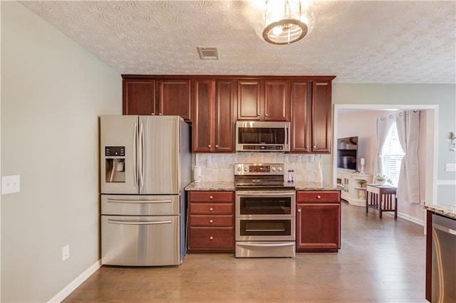 3370 Battlement Cir, Loganville, GA 30052 - kitchen with stainless steel appliances, a textured ceiling, wood finished floors, backsplash, and light stone counters