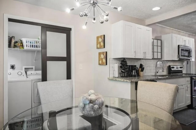 kitchen with stainless steel appliances, white cabinets, washer and clothes dryer, and decorative backsplash