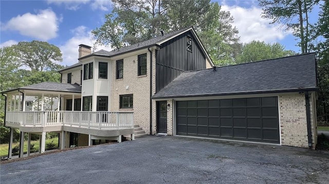 805 Wesley Oak Rd, Sandy Springs, GA 30328 - view of front of house with brick siding, a chimney, driveway, an attached garage, and board and batten siding