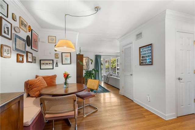 dining room featuring visible vents, light wood-style flooring, breakfast area, and ornamental molding