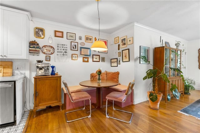 dining space featuring breakfast area, ornamental molding, and light wood finished floors