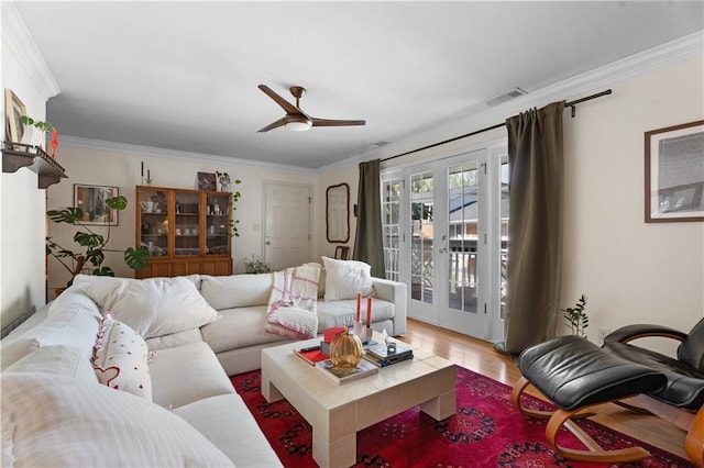 living area featuring a ceiling fan, wood finished floors, visible vents, french doors, and crown molding