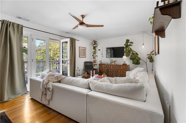 living area featuring visible vents, wood finished floors, a ceiling fan, and crown molding