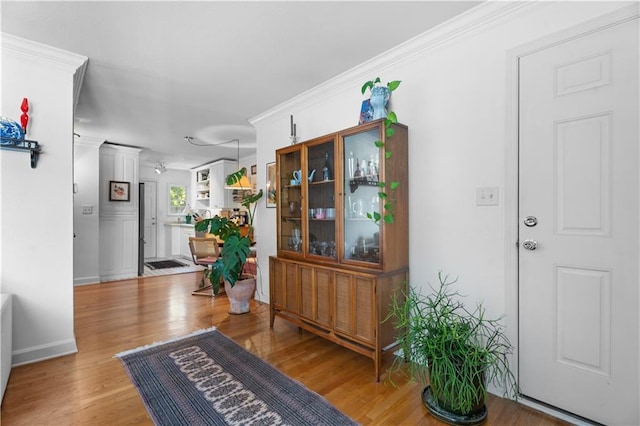 entryway with crown molding, baseboards, and wood finished floors