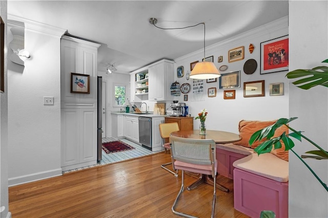 dining room with breakfast area, crown molding, and light wood finished floors