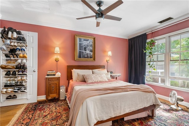 bedroom featuring visible vents, multiple windows, wood finished floors, and crown molding