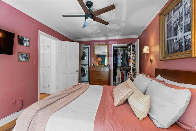 bedroom with a ceiling fan, baseboards, a closet, crown molding, and stacked washer / dryer