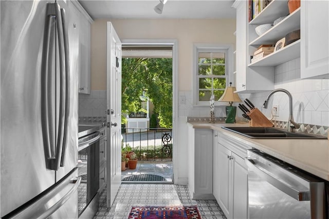 kitchen with open shelves, a sink, stainless steel appliances, light countertops, and white cabinets