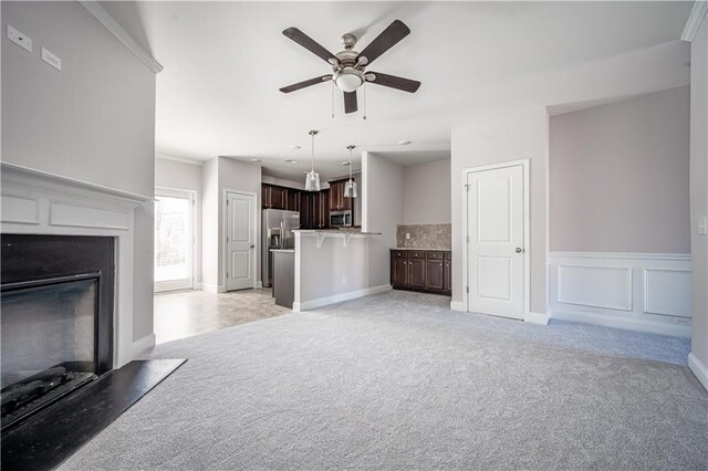2544 Castellan Dr, Atlanta, GA 30316 - unfurnished living room with light carpet, ceiling fan, a glass covered fireplace, and a wainscoted wall