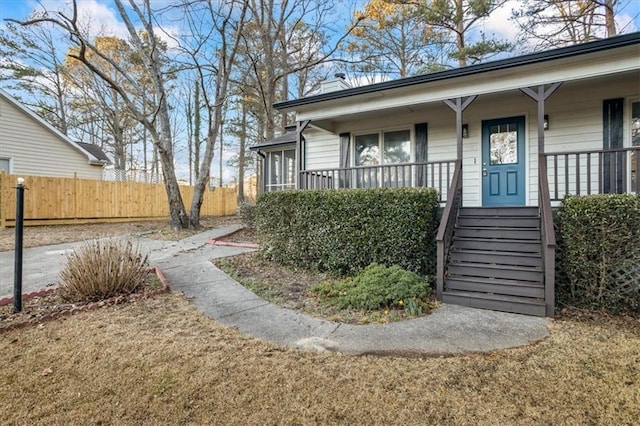 entrance to property with covered porch and a lawn