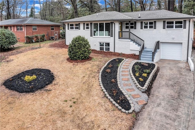 single story home featuring a garage, brick siding, driveway, and roof with shingles