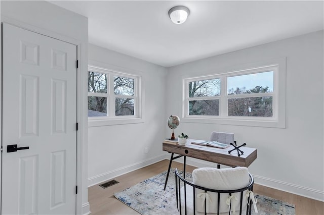 office space featuring baseboards, visible vents, and wood finished floors