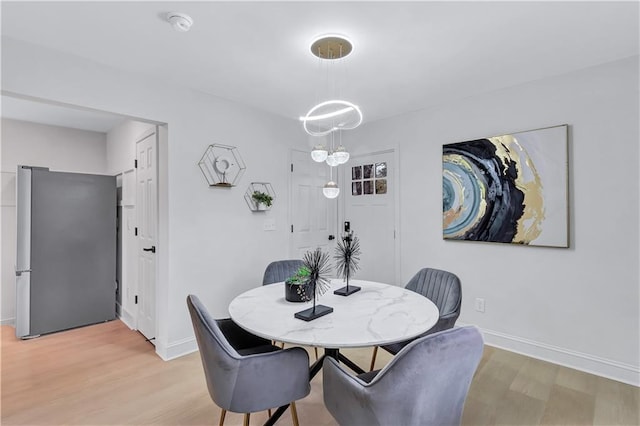 dining room featuring light wood-style floors, baseboards, and an inviting chandelier