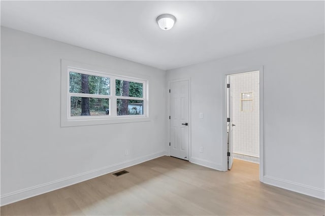 unfurnished room with light wood-style floors, visible vents, and baseboards