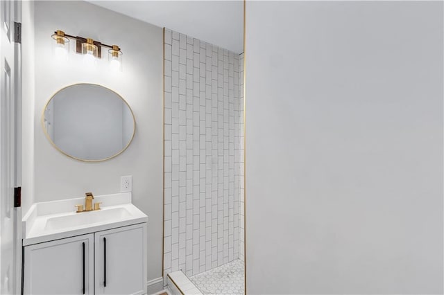 full bathroom featuring a tile shower and vanity