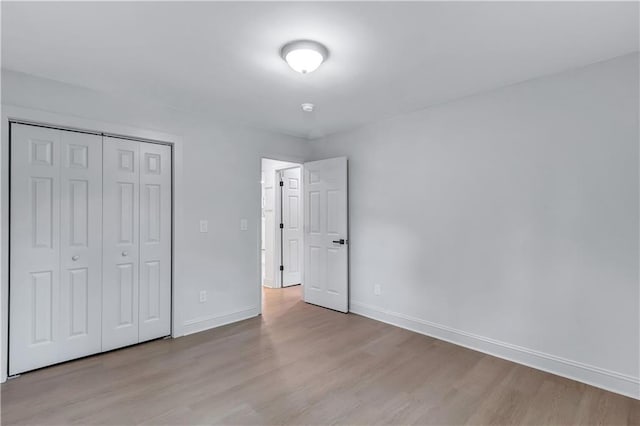 unfurnished bedroom with a closet, baseboards, and wood finished floors